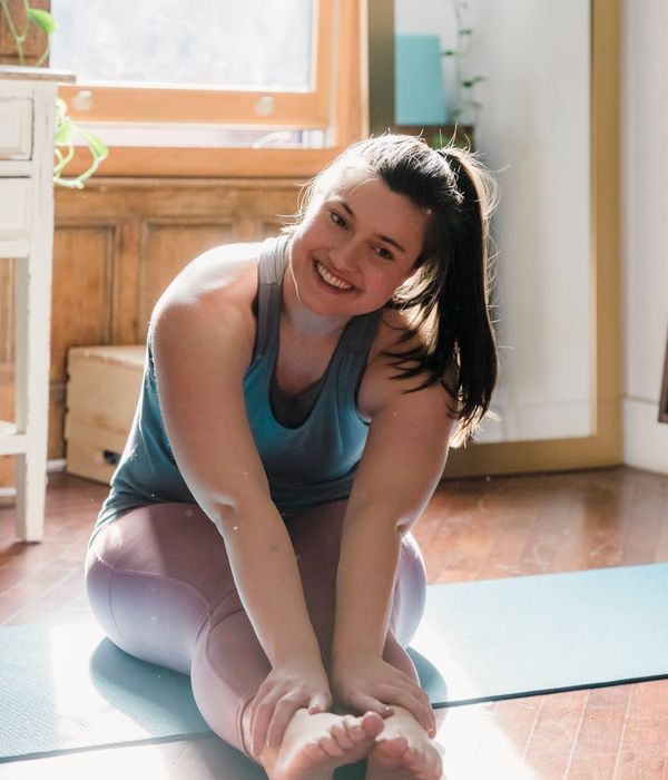 Woman smiling and stretching in a bright, peaceful room.